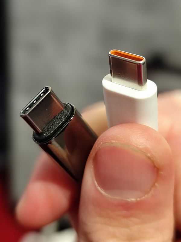 Two small oval USB-C plugs held between finger and thumb