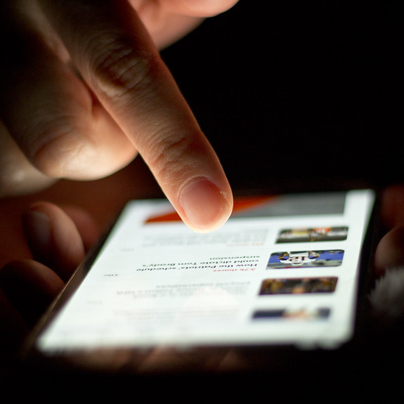 A fingertip touching the glowing screen of a smartphone