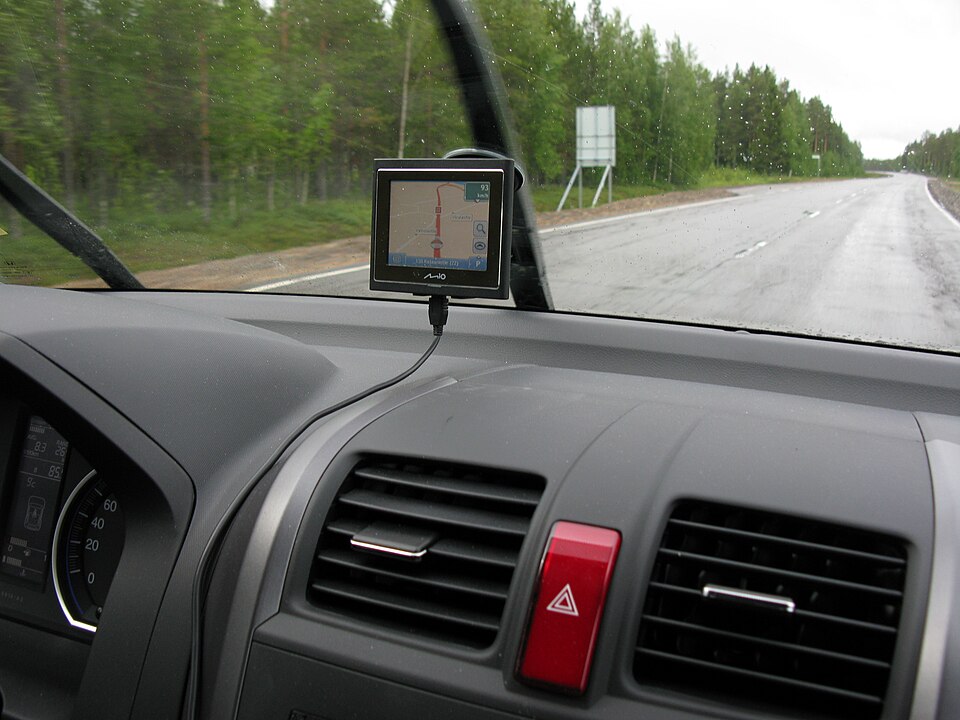A satellite navigation unit mounted on a car windscreen, showing a map