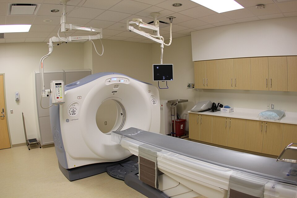 A hospital CT scanner: a large ring-shaped gantry with a patient table leading into it