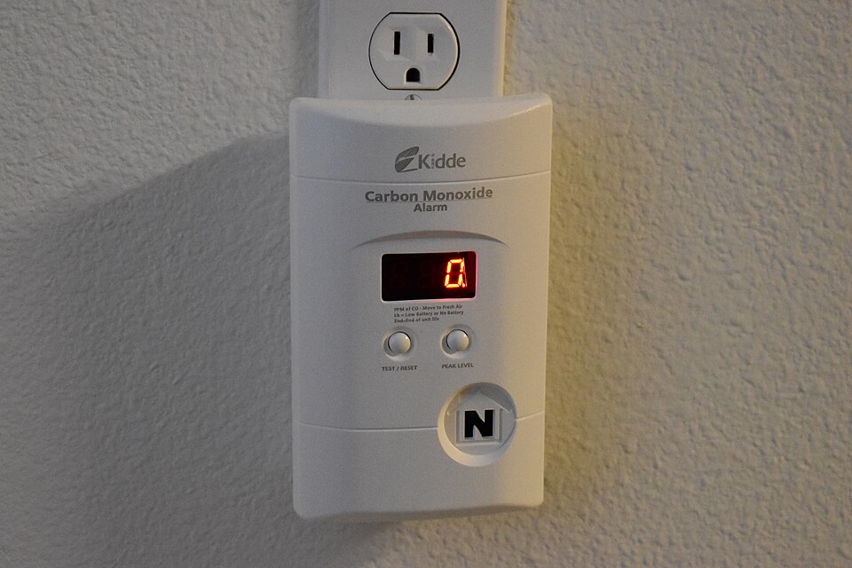 A carbon monoxide alarm plugged into a wall socket, showing a digital reading
