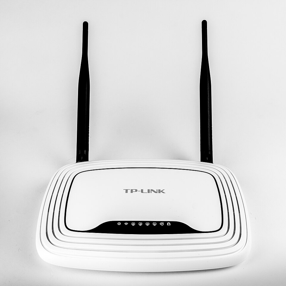 A white home wireless router with two antennas and a row of status lights