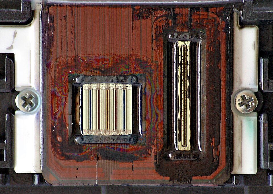 Close-up of an inkjet print head showing rows of nozzle strips for coloured and black ink