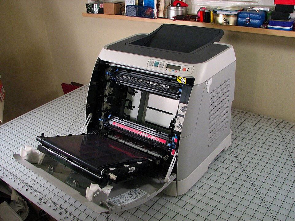 A colour laser printer with its front door open, showing the toner cartridges and transfer belt