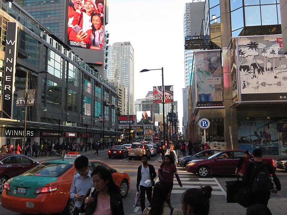 A busy city square with large bright video billboards on the buildings