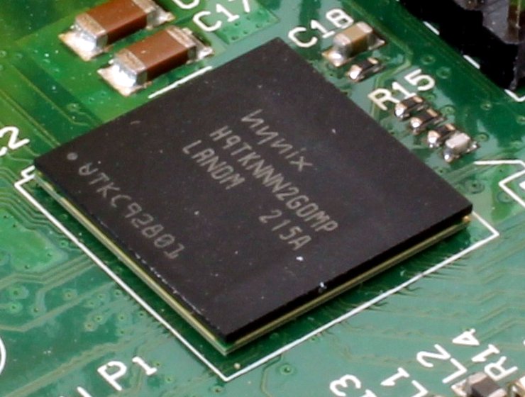 Close-up of a square black chip soldered onto a green circuit board