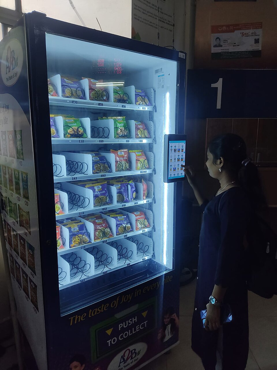 A snack vending machine with spiral coils holding packets and a touch screen for choosing items