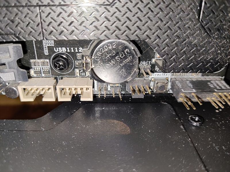 A round coin-cell battery mounted on a computer motherboard
