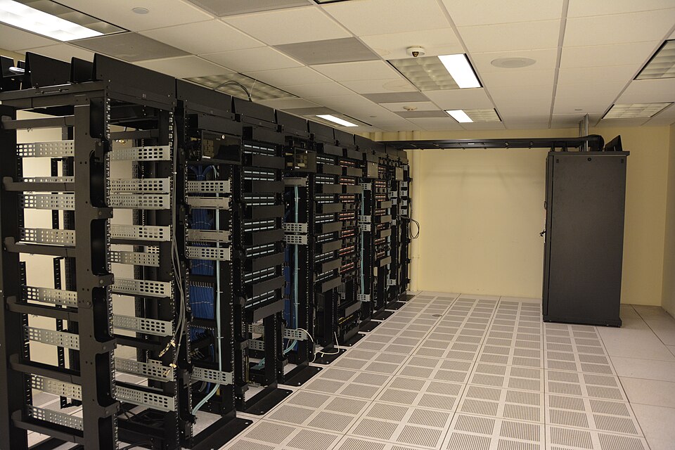 Rows of black server racks on a raised tiled floor in a data centre