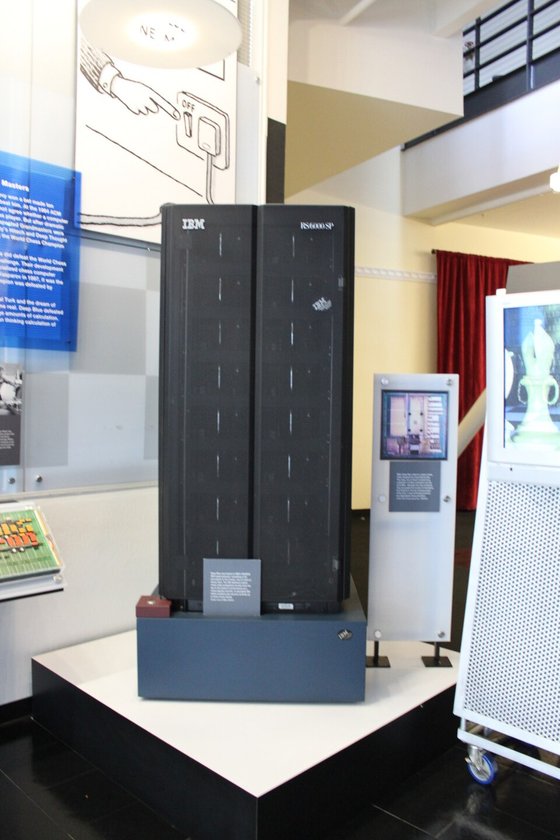 A tall black computer cabinet displayed in a museum, labelled as the chess computer that beat a world champion