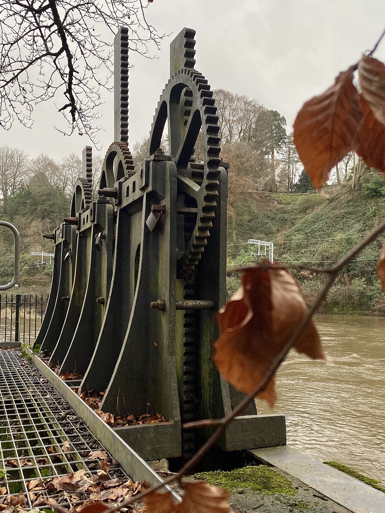 A row of large meshing metal gears with interlocking teeth on a steel frame.
