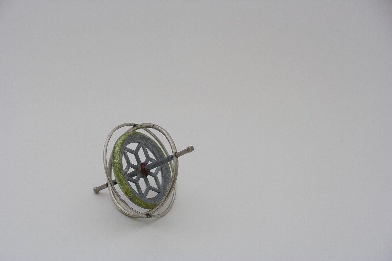 A metal toy gyroscope: a spinning wheel held inside two pivoting rings.