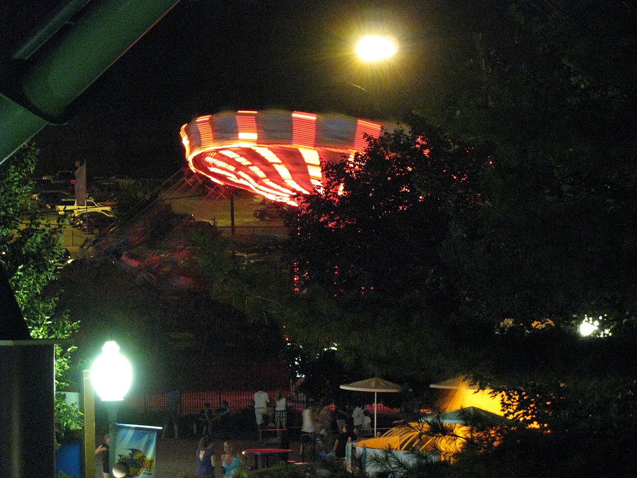 A swing carousel lit up at night, its hanging chairs flung outward as the roof spins.